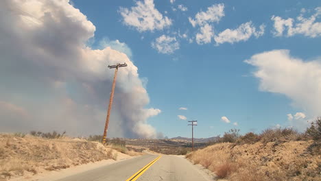 Conducción-De-Automóviles-En-Una-Carretera-De-Campo-Viendo-La-Nube-De-Humo-De-Fuego-De-Fairview-En-El-Horizonte