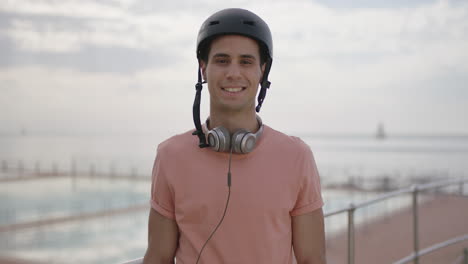 Retrato-De-Un-Joven-Atractivo-Con-Casco-Sonriendo-Tímido-Fondo-Costero