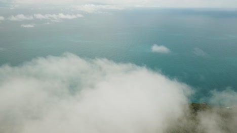 antena de drones sobre las nubes que bajan a una isla tropical con agua azul en verano