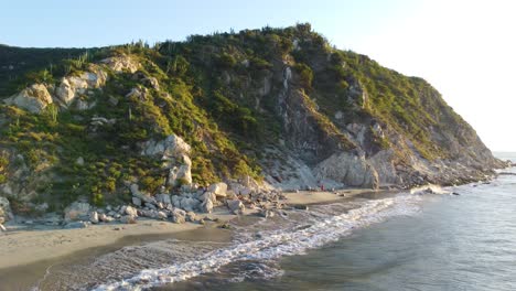 Strand-Von-Santa-Marta-Mit-Wellen,-Die-Ans-Ufer-Plätschern,-üppig-Grüne-Hügel,-Sonniger-Tag,-Luftaufnahme