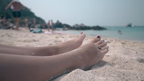 Frauenbeine-Und--füße,-Bedeckt-Mit-Trockenem-Sand,-Liegen-An-Der-Küste