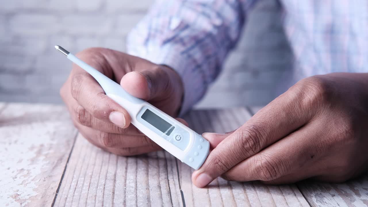 Persona che Misura la Propria Temperatura con un Termometro Digitale
