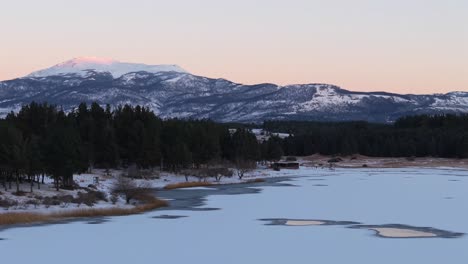 backward panoramic drone movement at laguna la zeta with snowy lake shore with forest, esquel, province of chubut, argentina