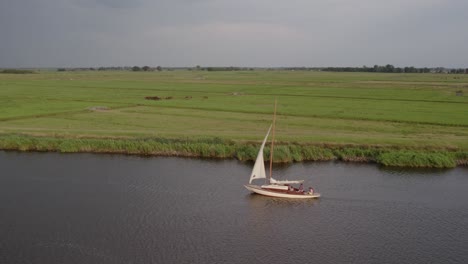 Sail-boat-cruising-on-calm-water-at-Alde-feanen-national-park,-aerial