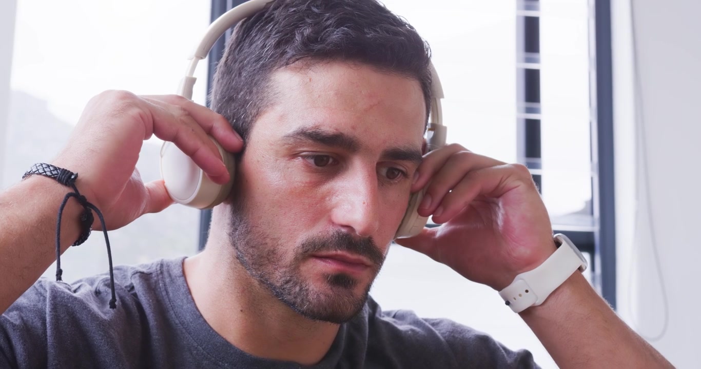 Hombre en la colchoneta, localizando auriculares, estirándose, recogiéndolos, revisándolos, poniéndoselos, agarrando el teléfono para empezar a entrenar.