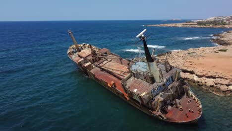 drone shot of an abandoned old ship, stranded next to the coast