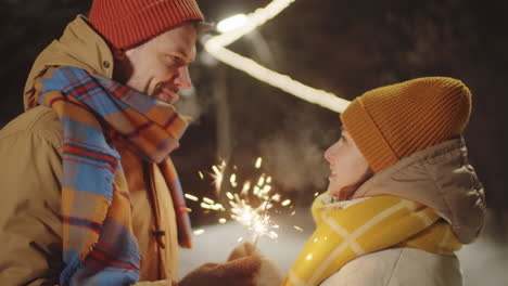 pareja romántica de pie con bengalas navideñas al aire libre