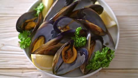 fresh mussels with herbs in a bowl with lemon