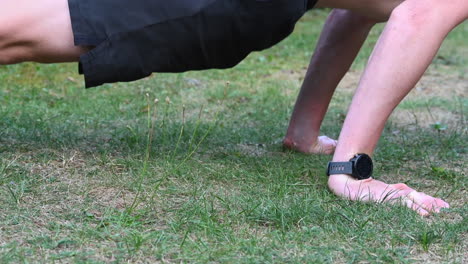 a young calisthenics athlete is doing pushups on a grassy ground in his garden