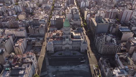 Aerial-Approaching-shot-of-historic-National-Congress-in-Buenos-Aires-and-driving-cars-on-sun-lighting-road-in-city