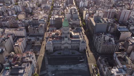 aerial approaching shot of historic national congress in buenos aires and driving cars on sun lighting road in city