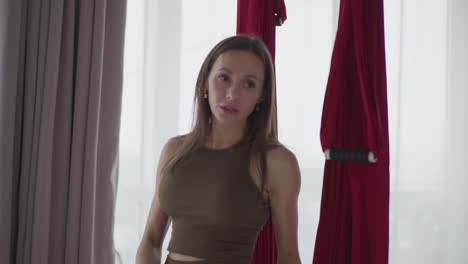 yoga instructor converses with student after intense session under red aerial silks in bright studio sharing feedback encouragement focusing on calm reflective moment breathing balance wellness