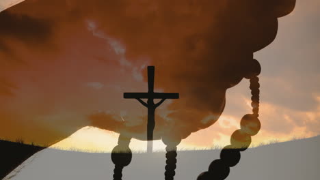 animation of christian cross and hands holding rosary over landscape with clouds background