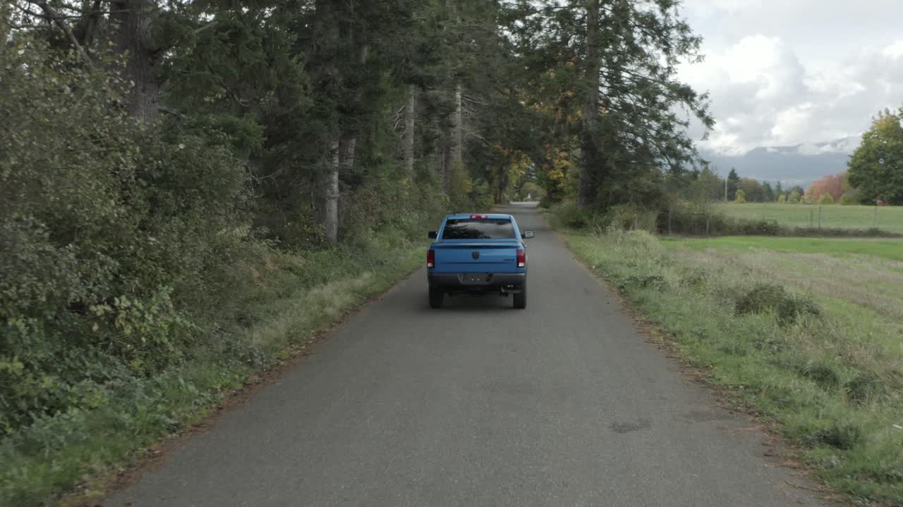 Blue RAM pickup truck driving along rural road