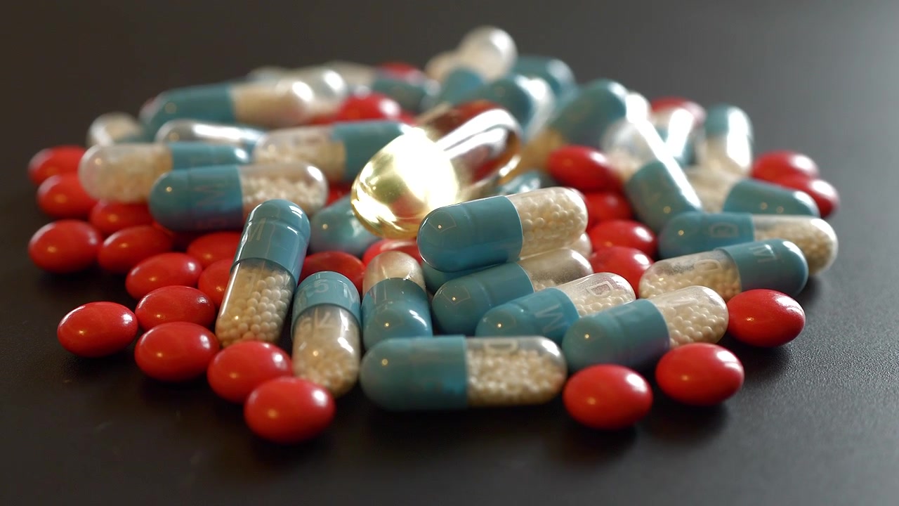 Pile of Assorted Medical Capsules and Tablets on Dark Surface