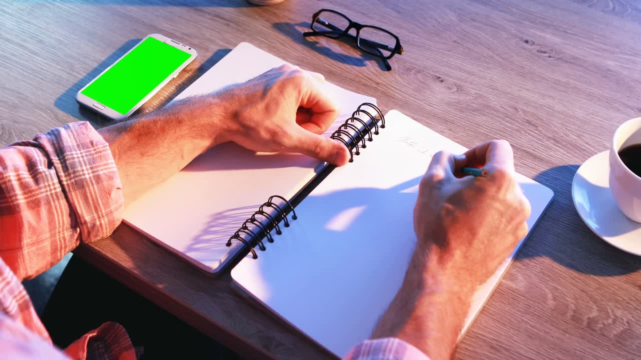 Male executive writing in diary at his desk 4k