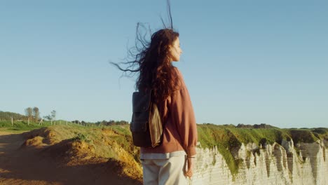 woman hiking on a cliff overlooking the ocean