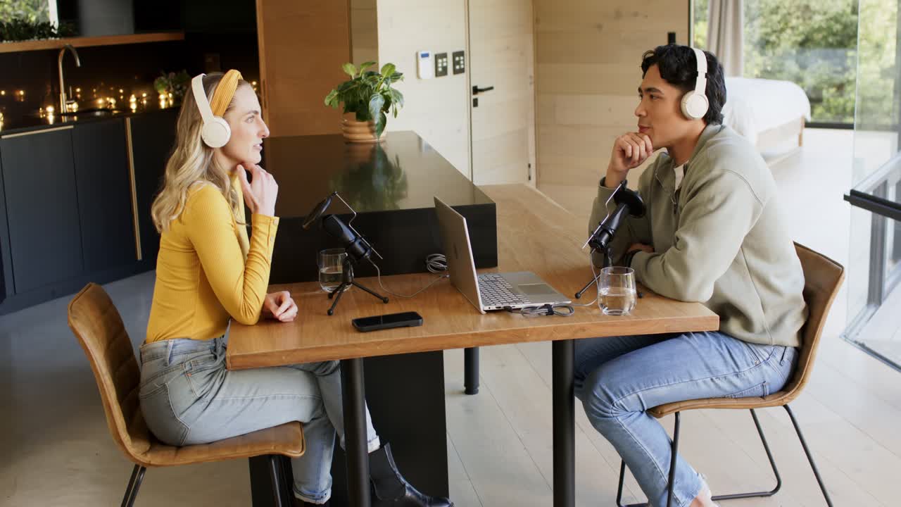 Un conduttore asiatico e una co-conduttrice provano i microfoni e parlano in studio dopo aver ricevuto una domanda.