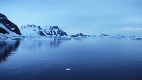 Blaue-Winterlandschaft-Mit-Meer-Und-Bergen-In-Der-Antarktis,-Reflexionen-über-Ruhiges,-Stilles-Meerwasser,-Globale-Erwärmung-Und-Klimawandel-An-Der-Küste-Der-Antarktis