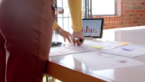 Midsection-of-african-american-casual-businesswoman-looking-at-documents-in-office,-slow-motion