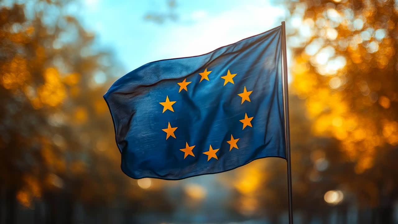 European Union flag waving in the breeze. The European Union flag flutters against a backdrop of golden autumn leaves in a peaceful setting
