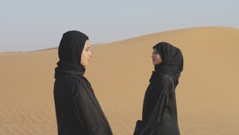 Zwei-Schöne-Muslimische-Frauen-Im-Hijab-Stehen-In-Einer-Windigen-Wüste