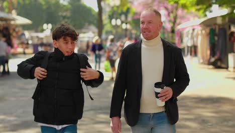 Two men walking and interacting in an urban outdoor setting