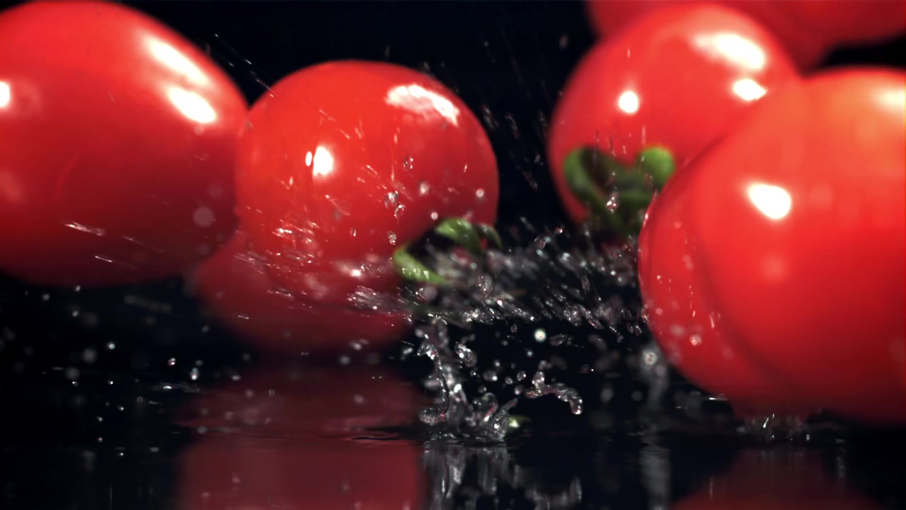 Fresh Cherry Tomatoes Falling into Water with Splashes