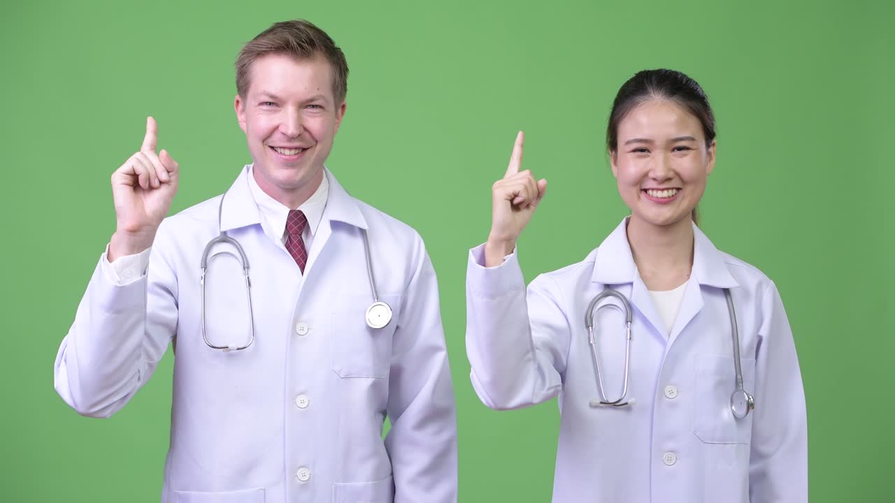 Multi-ethnic couple doctors pointing up together