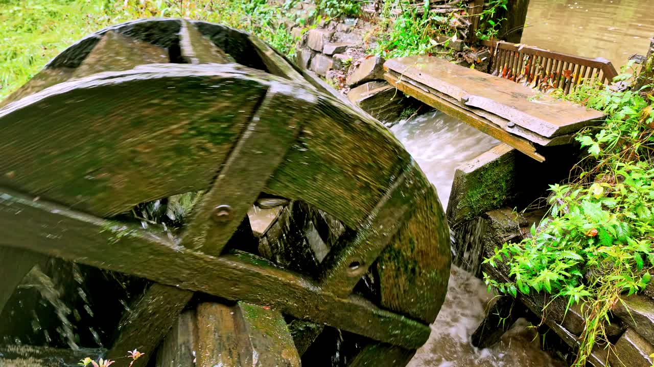 Gushing sluice water turns powerful mechanical mill wheel
