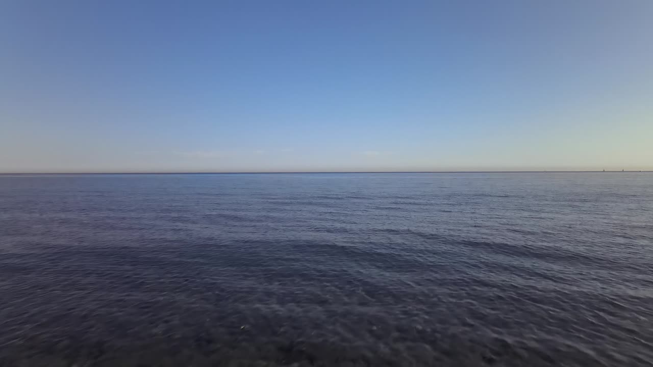 Forward dolly shot from the beach to the ocean with man enjoying the view