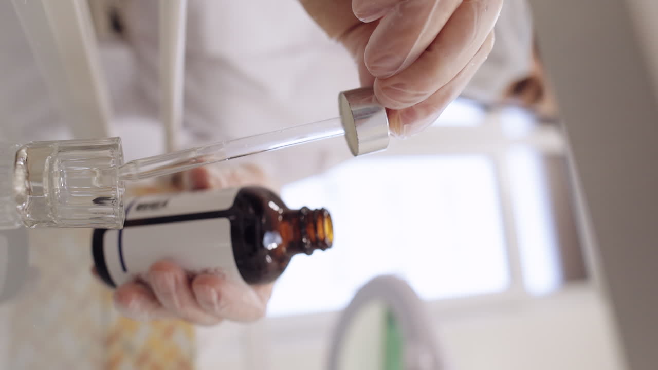 Moisturizing medical peeling cream essence pouring drips from bottle into glass pipette in hands