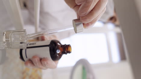 moisturizing medical peeling cream essence pouring drips from bottle into glass pipette in hands