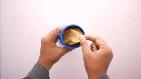 hand holding a container of potato chips