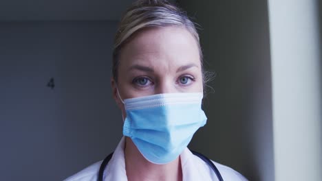 Portrait-of-caucasian-female-doctor-wearing-face-mask-at-hospital