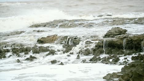 stones lie in a raging sea under blows of big waves