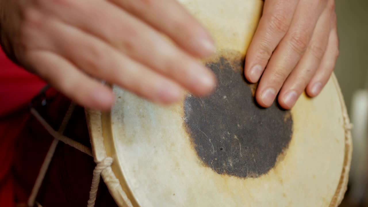 Close up of hands of a man playing a drum.