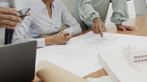 african american architects discussing blueprints and using tablet in office in slow motion