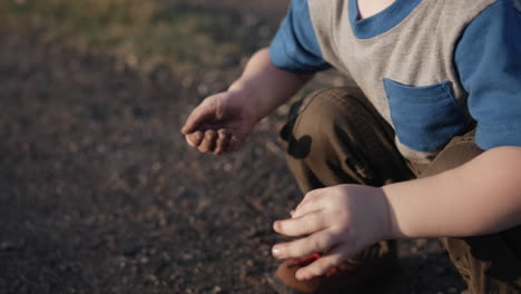 happy young boy playing outside with dirt in sunset sunlight in cinematic slow motion