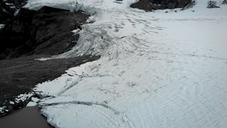 sobrevuelo aéreo sobre el hielo y el lago glacial del glaciar claridenfirn en uri, suiza, al final de un día con una vista de gran altitud de picos alpinos y icebergs flotando en el agua.