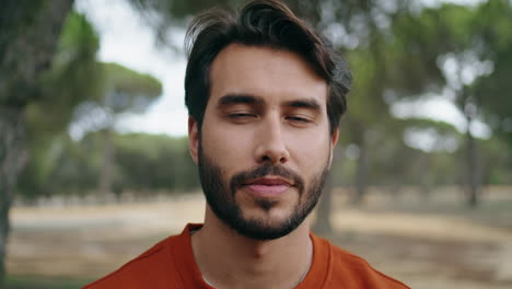 Vertical-portrait-happy-bearded-man-looking-camera-with-smile-at-forest-alone.