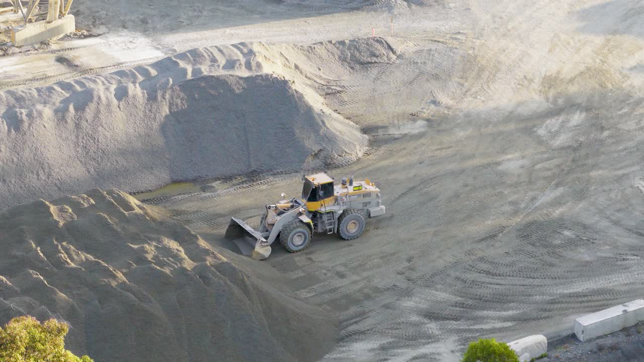 Aerial footage of a loader moving soil in a Gold Coast quarry under bright daylight