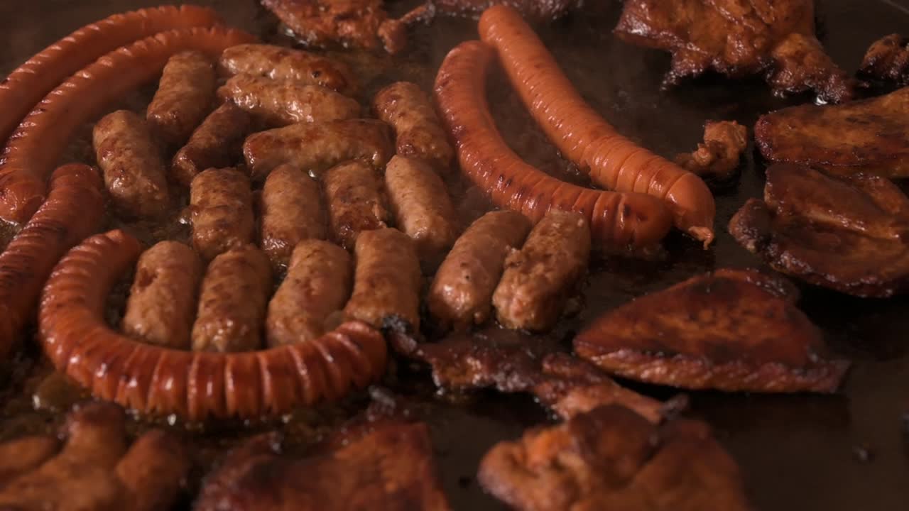 salchichas, cevapi y carne de chuck en una sartén - cámara lenta