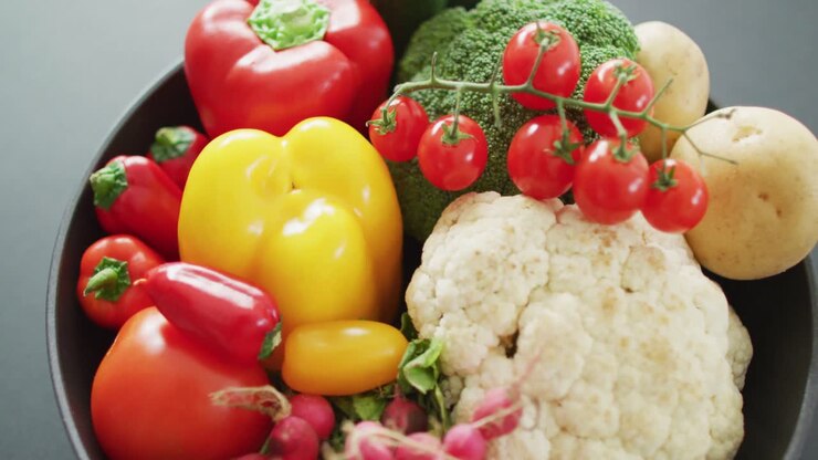 Video of close up of fresh vegetables in pan over grey background