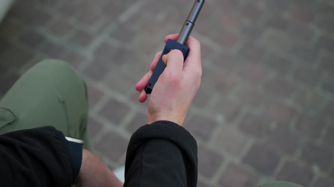vista de cerca de la abrazadera plegable unida al teléfono móvil y extendiendo el palo de selfie para presionar el botón