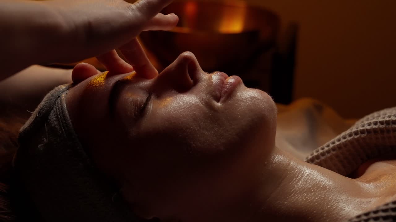 Kvinde får afslappende ansigtsmassage i en spa