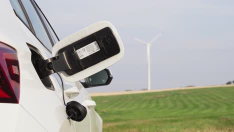 opened car gas or fuel tank lid and windmill in background, petrol and diesel is expensive, electromobility is future