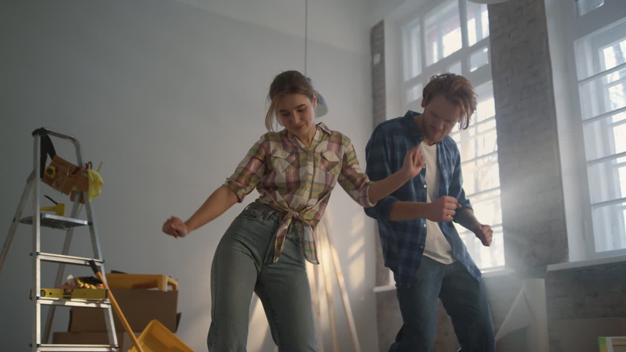 Joyful family enjoying improvement of apartment. Happy couple dancing indoors.