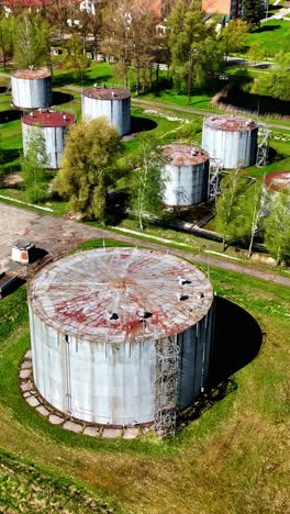Rusty and old silos near small town, aerial vertical view