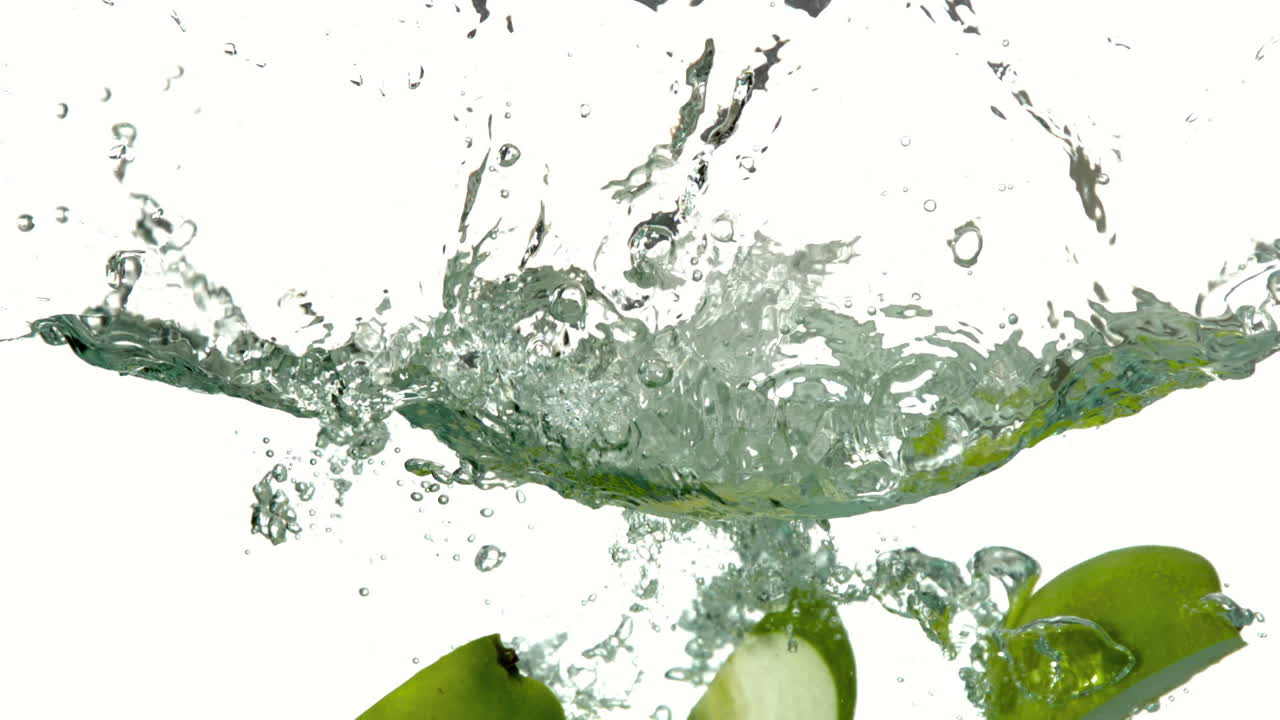 Apple quarters plunging into water on white background